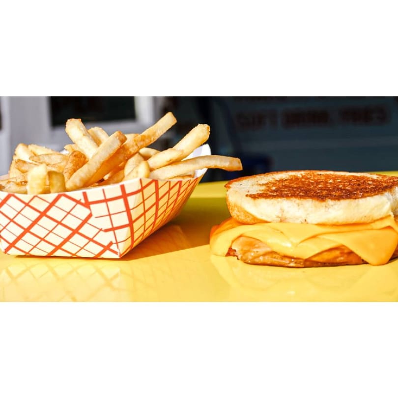Patty Smash Brand grilled cheese sandwich with melted cheese and a side of golden fries.