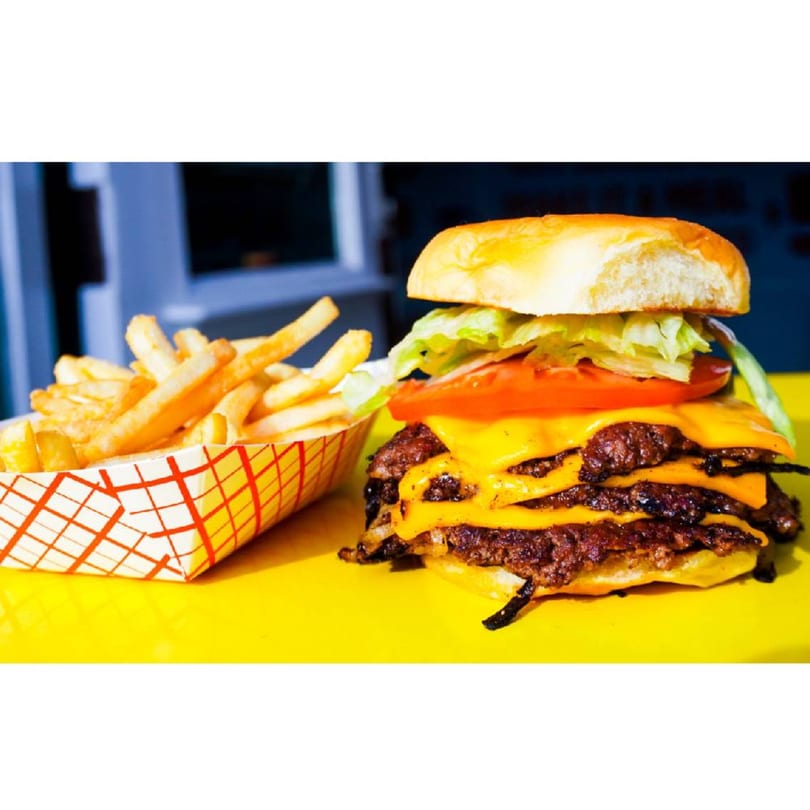 A Patty Smash Brand double cheeseburger with lettuce, tomato, and a side of fries.